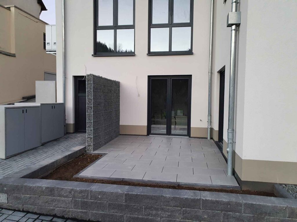 Terrasse aus Fliesen, Beet und neu gesetzter Mauer