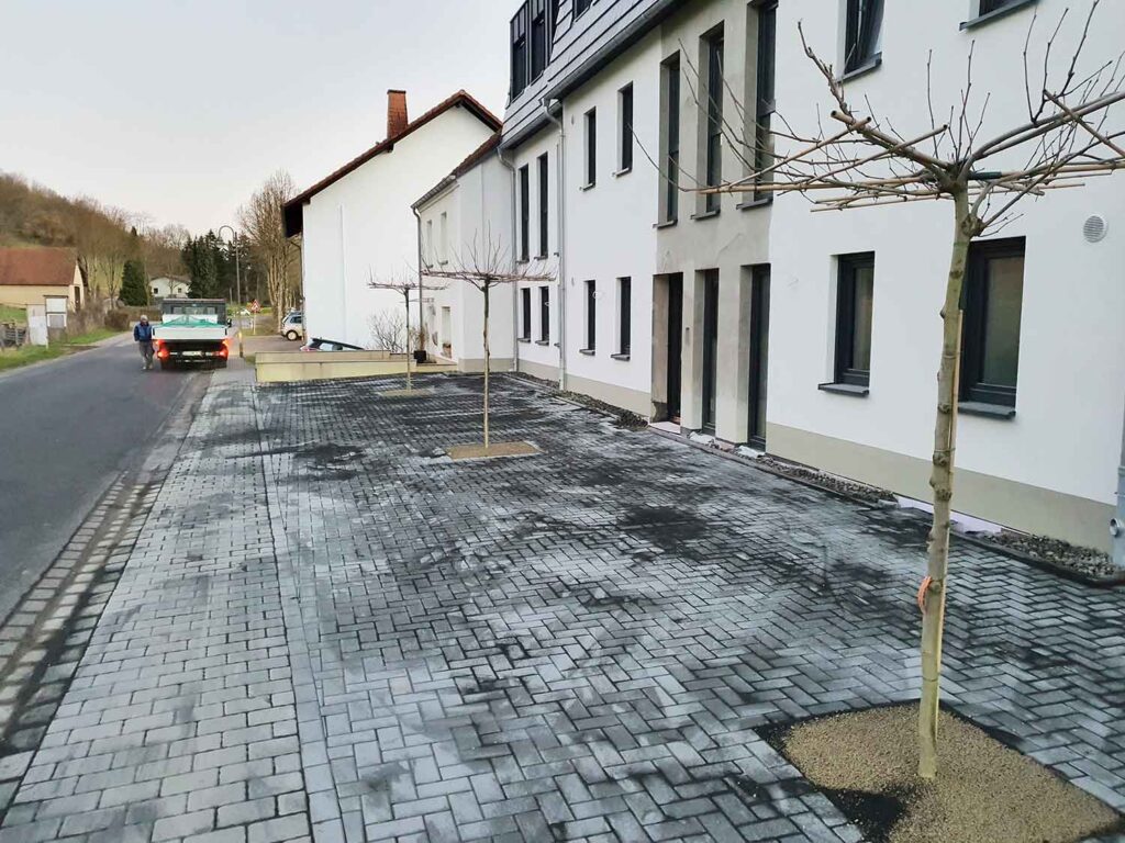 großer gepflasterter Bereich aus unterschiedlichen Pflasterarten vor einem Mehrfamilienhaus