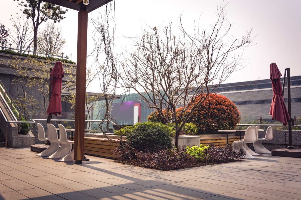 Terrasse mit winterlichen Bäumen und Sträuchern und weißen Plastikstühlen