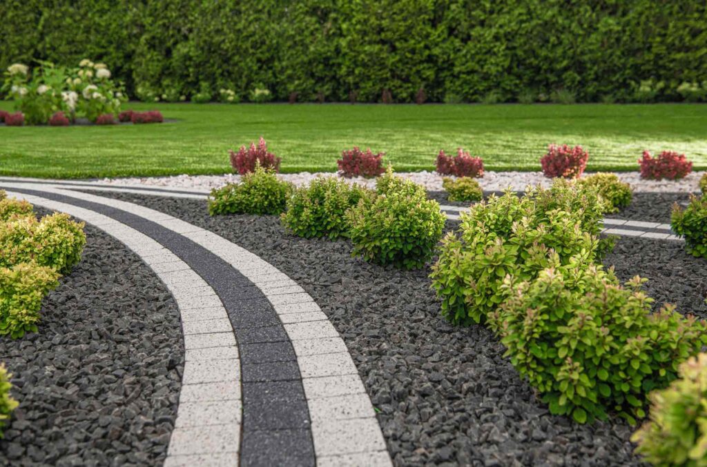 Pflaster in einem Garten mit Büschen und gepflegter Rasenfläche