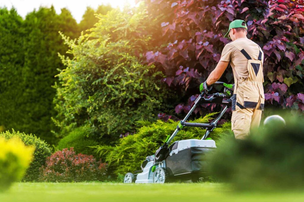 Mann mäht den Rasen in einem schönen Garten