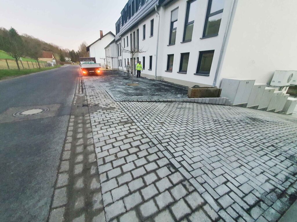 großer gepflasterter Bereich aus unterschiedlichen Pflasterarten vor einem Mehrfamilienhaus