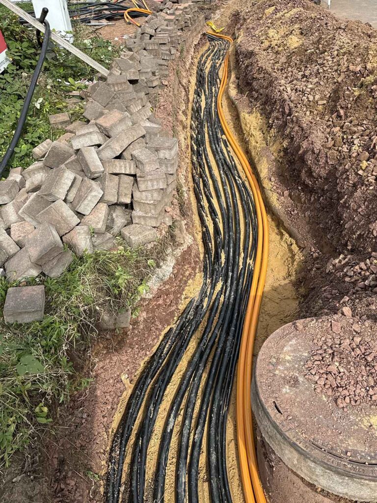 Orangene und schwarze Glasfaser Kabel liegen im Boden