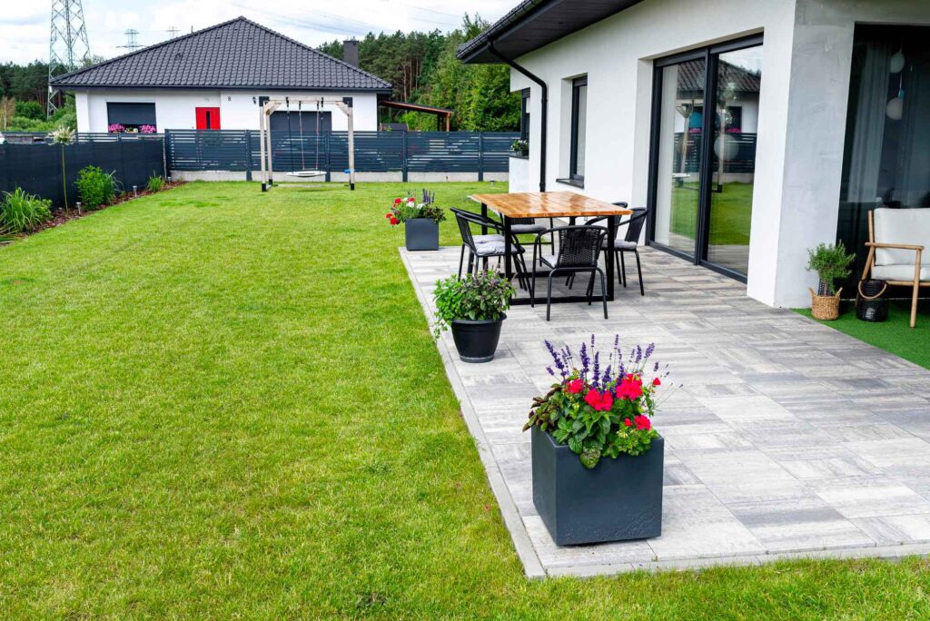 Terrasse mit Holztisch in einem schön angelegten Garten mit kleinen Hochbeeten und Sichtschutz
